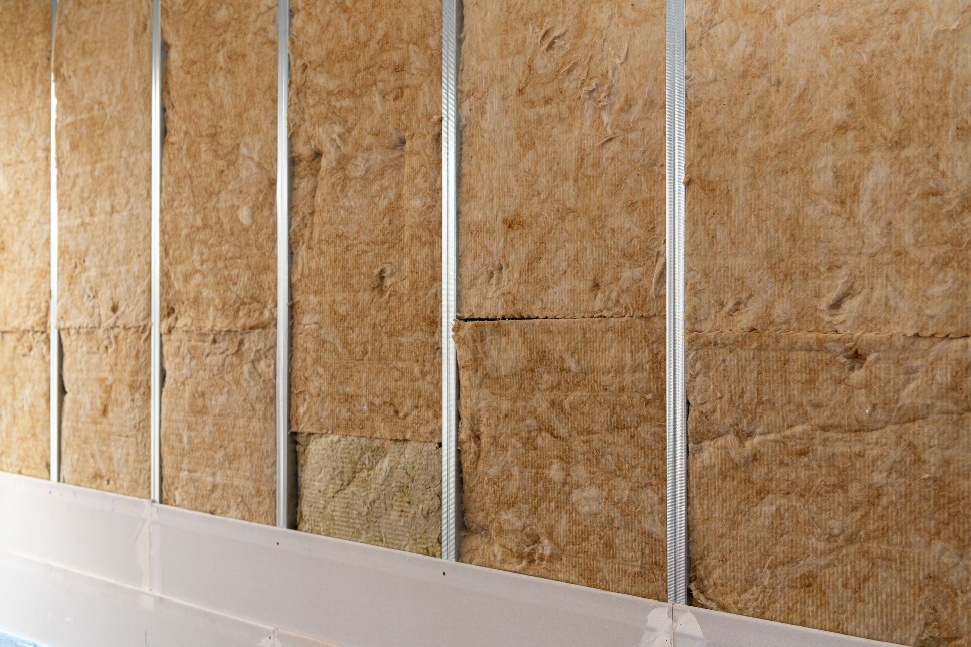 Isolation en laine de verre installée entre les montants métalliques verticaux d'une pièce en construction.