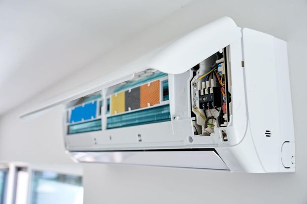 Aire acondicionado de pared abierto, con componentes internos a la vista y un panel de cableado de colores