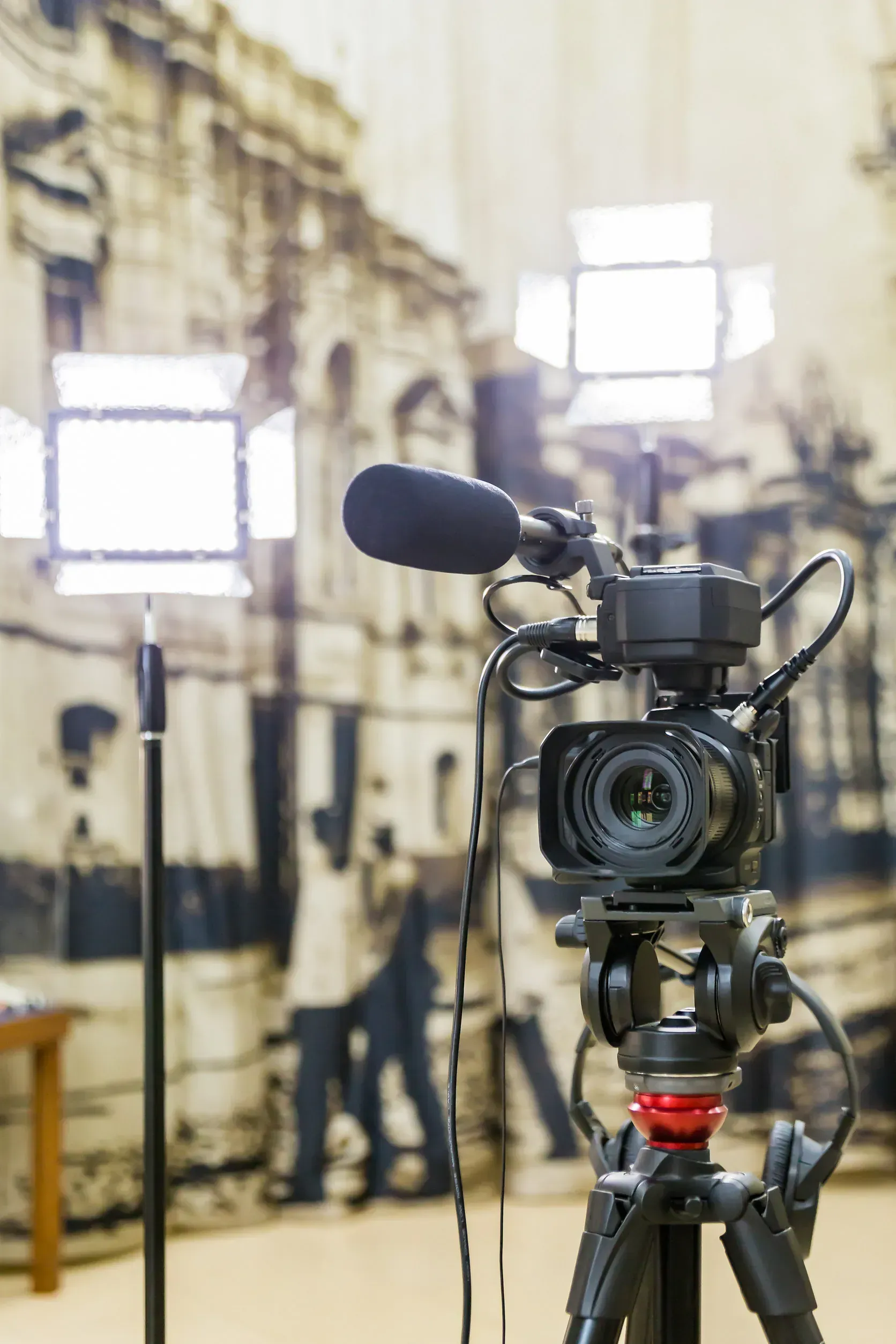 Cámara instalada con micrófono e iluminación frente a un fondo que representa una escena histórica.