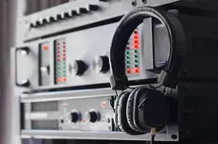 Auriculares colgados en rack de equipos de audio con perillas y luces.