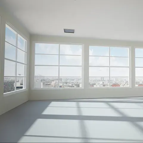 Habitación vacía y luminosa, con grandes ventanales con vistas a la ciudad. Las sombras de las ventanas se proyectan sobre el suelo pálido.