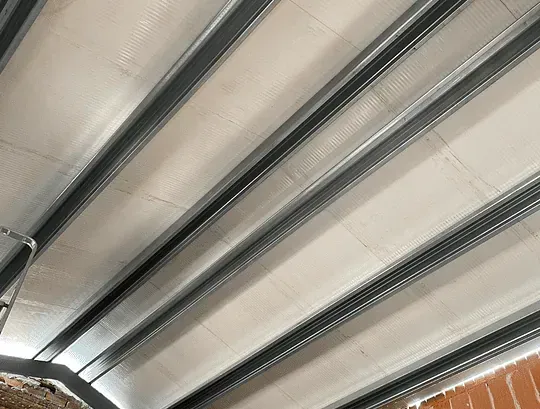 Techo en construcción; vigas de metal se extienden a través de paneles aislantes blancos.