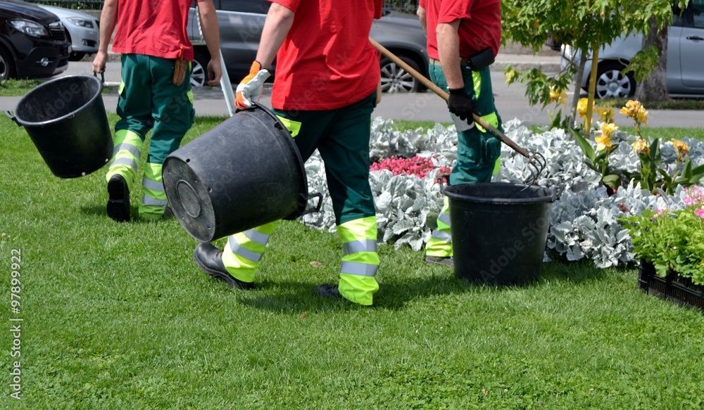 Un groupe de personnes travaille dans un jardin avec des seaux et des pelles.