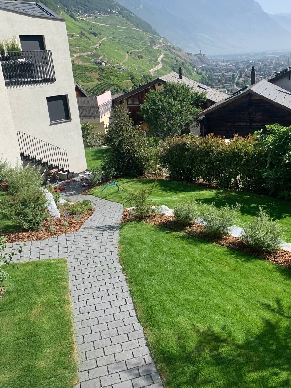 Une allée en briques menant à une maison avec une pelouse verte luxuriante.