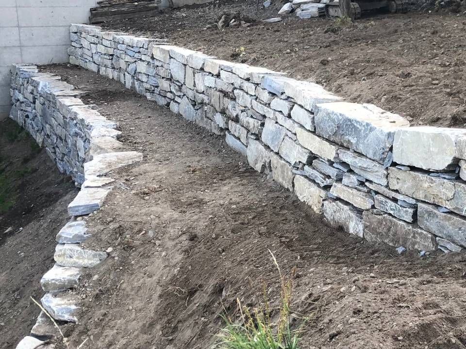 Un mur de pierre est en train d'être construit au sommet d'une colline de terre.