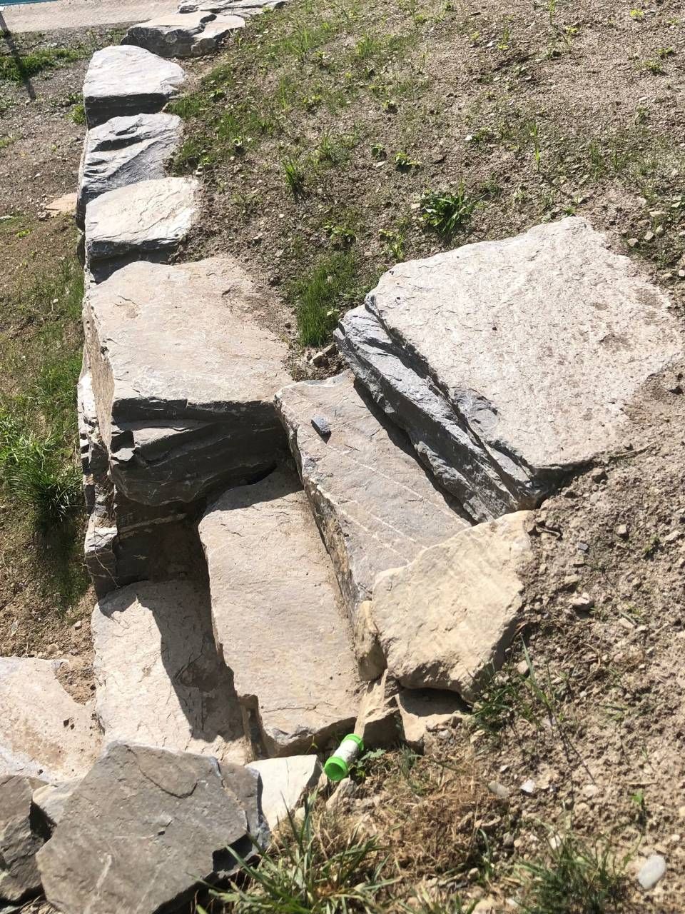 Une rangée de rochers posée sur un champ de terre.