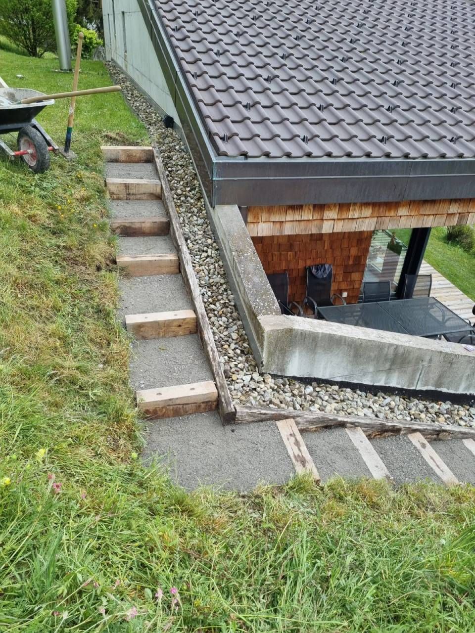 Une brouette est garée à côté d'un escalier menant à une maison.