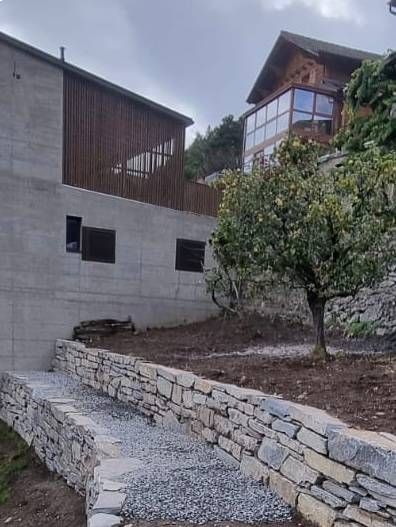 Un mur de pierre entoure une maison sur une colline.
