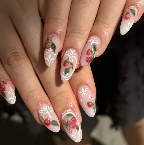 Un primer plano de las uñas de una mujer con fresas pintadas en ellas.
