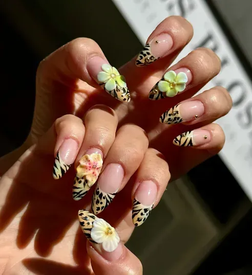 Las uñas de una mujer están decoradas con flores y estampado de leopardo.