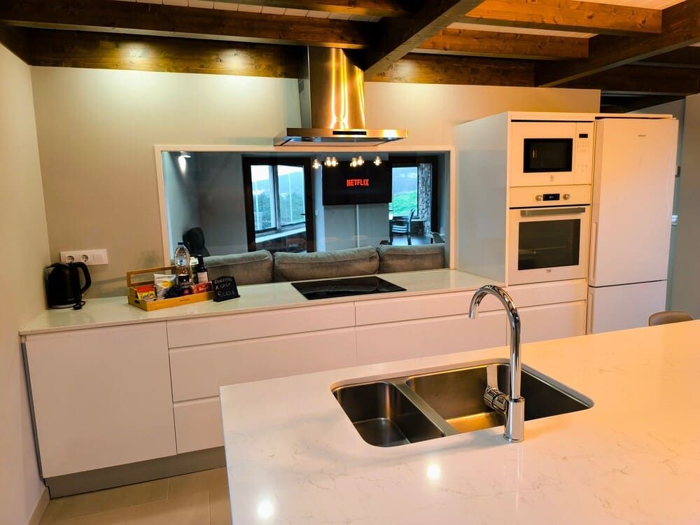 Una cocina con un fregadero y un televisor de Netflix en la pared.