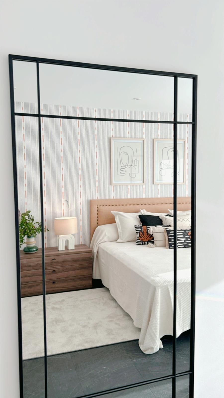 Un dormitorio con un espejo de cuerpo entero colgado en la pared.