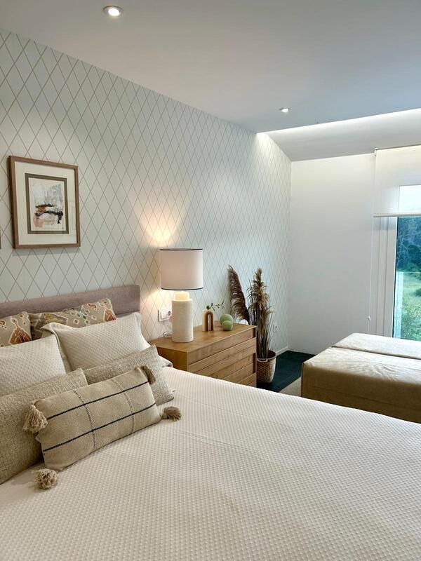 Un dormitorio con una cama, cómoda, lámpara y dos camas.