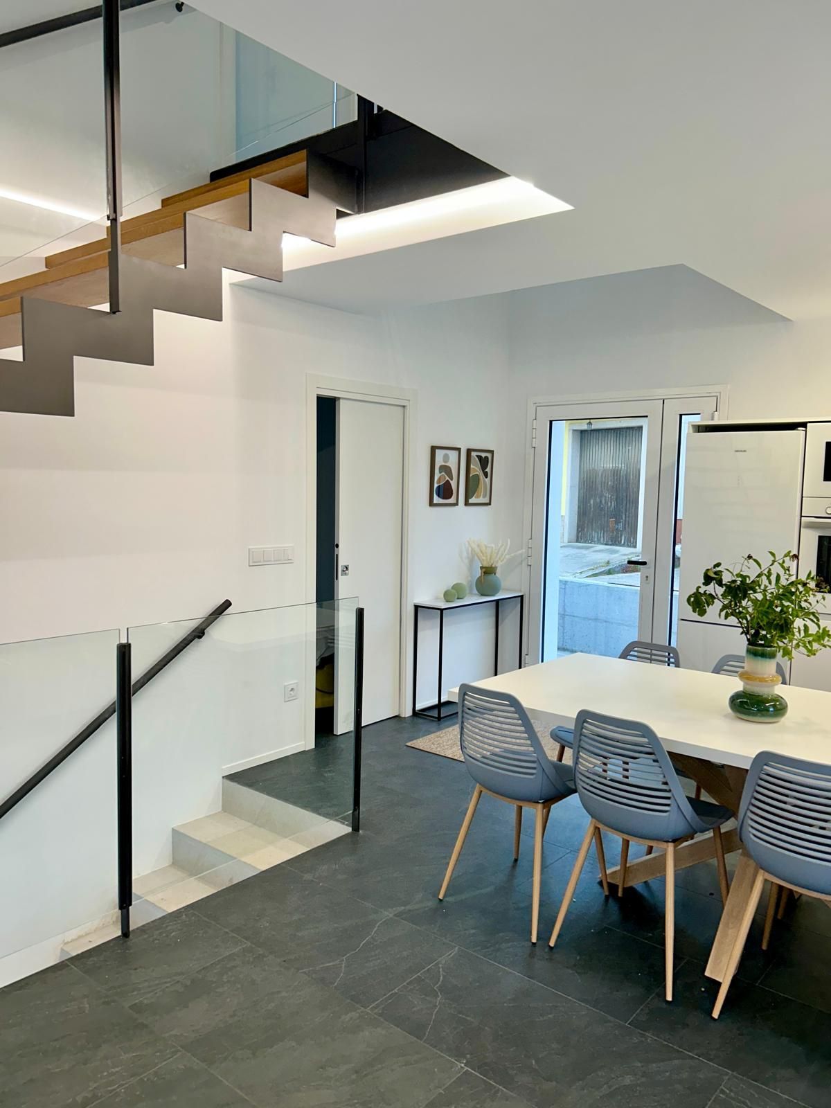 Un comedor con mesa y sillas y escaleras que conducen al segundo piso.