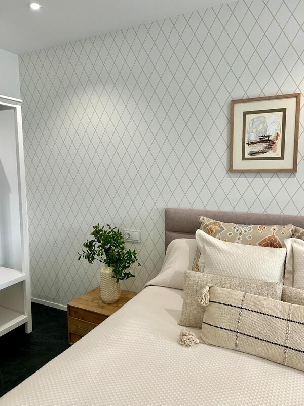 Un dormitorio con una cama, una mesita de noche y un cuadro en la pared.