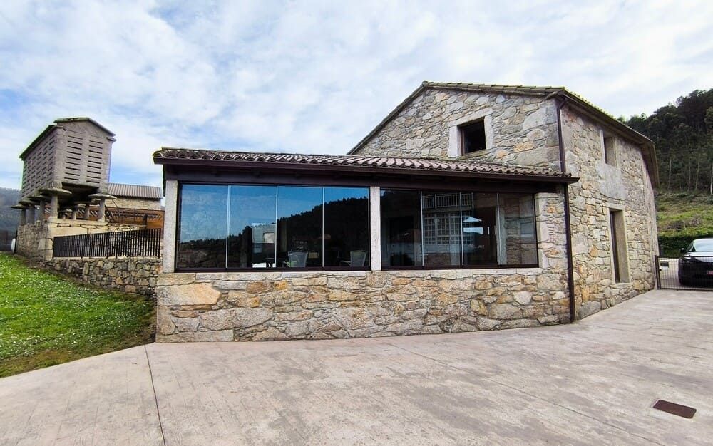 Una casa de piedra con un coche aparcado delante.