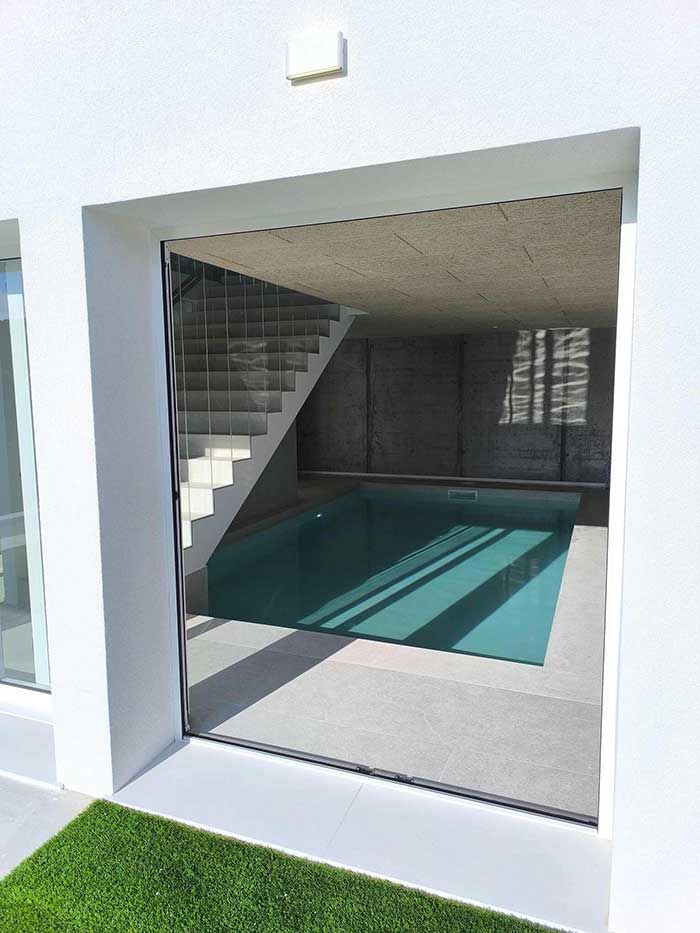 Una piscina está detrás de una puerta de vidrio en una casa.