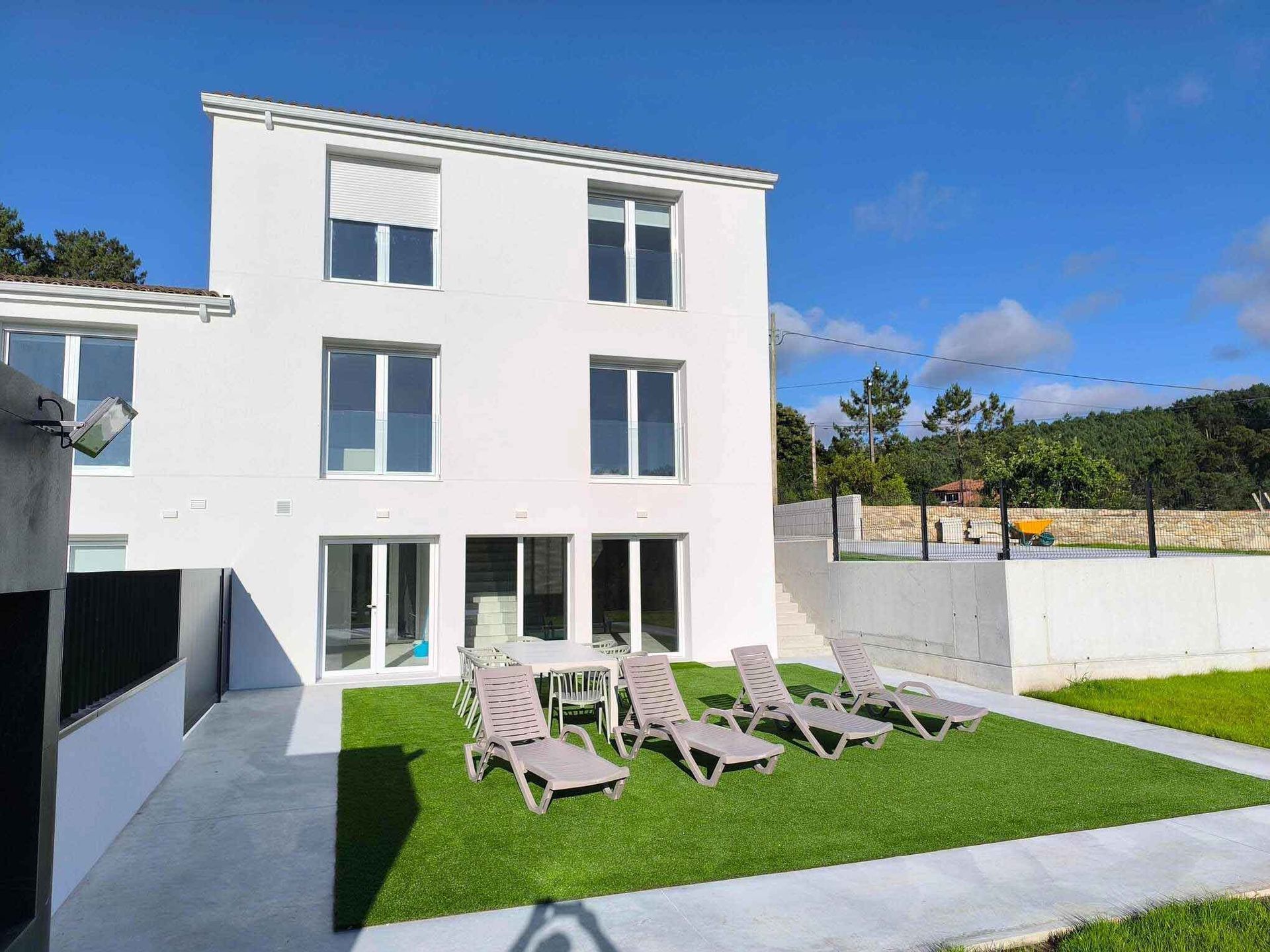 Una casa blanca con césped y sillas delante.