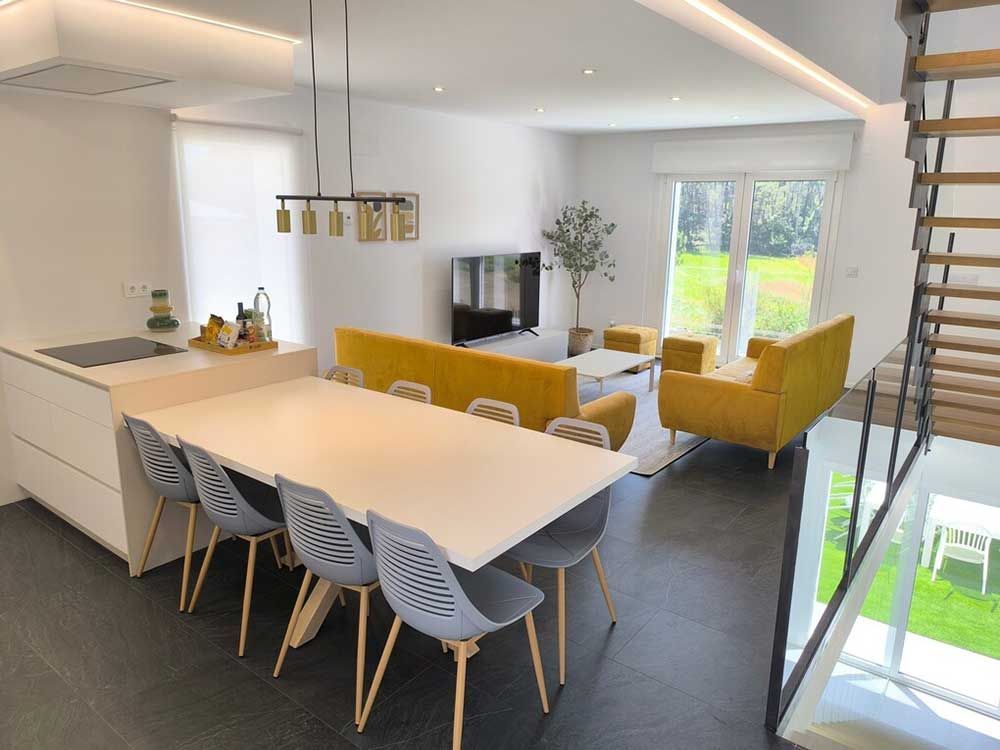 Una sala de estar con una mesa y sillas y un sofá amarillo.