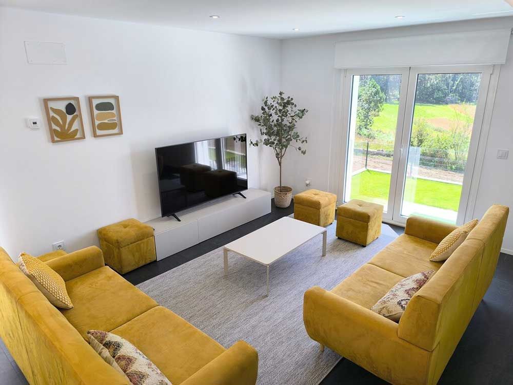 Una sala de estar con sofás amarillos y un televisor de pantalla plana.