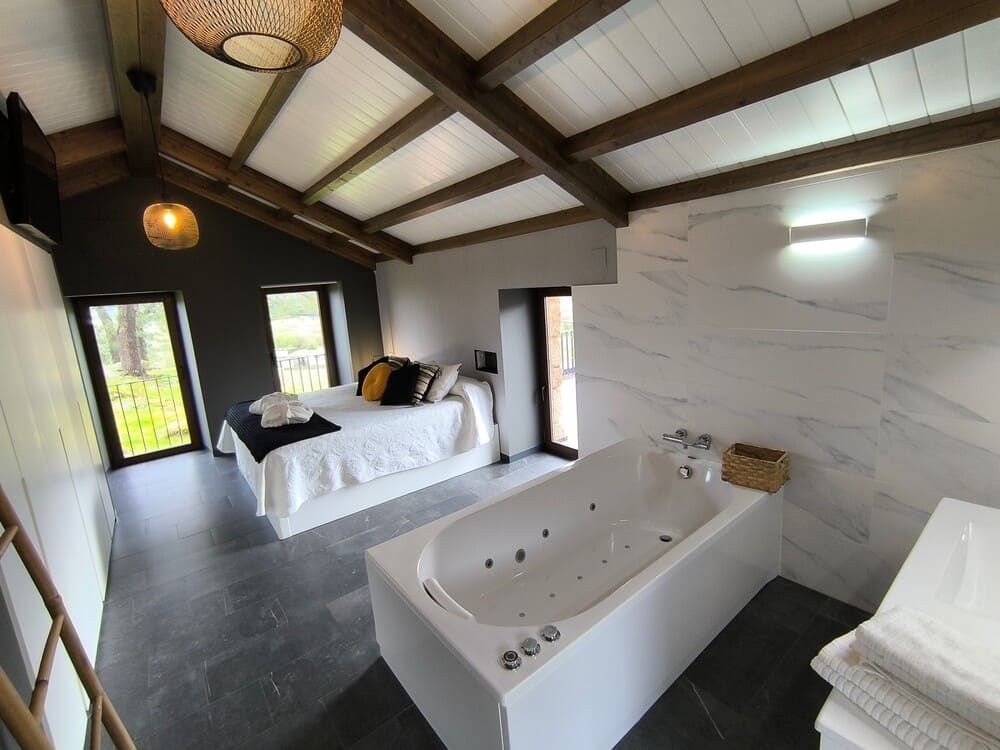 Un baño con bañera de hidromasaje y una cama.