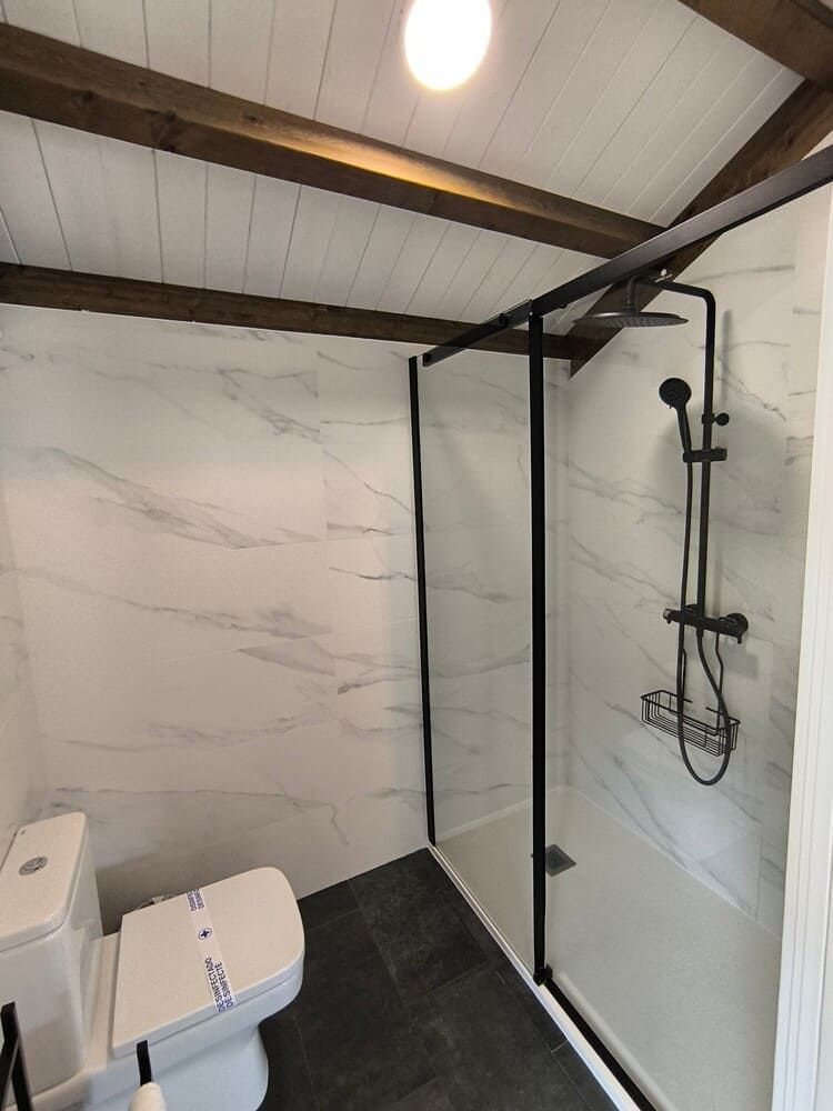 Un baño con inodoro y ducha a ras de suelo.