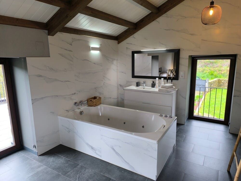 Un baño con bañera, lavabo, espejo y ventana.