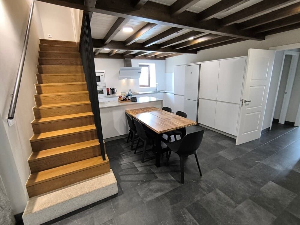 Una cocina con una mesa y sillas y unas escaleras que conducen a ella.