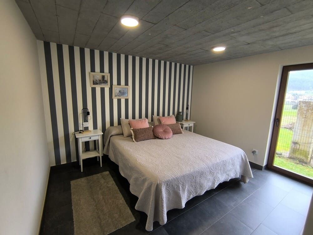 Un dormitorio con una pared rayada y una cama grande.