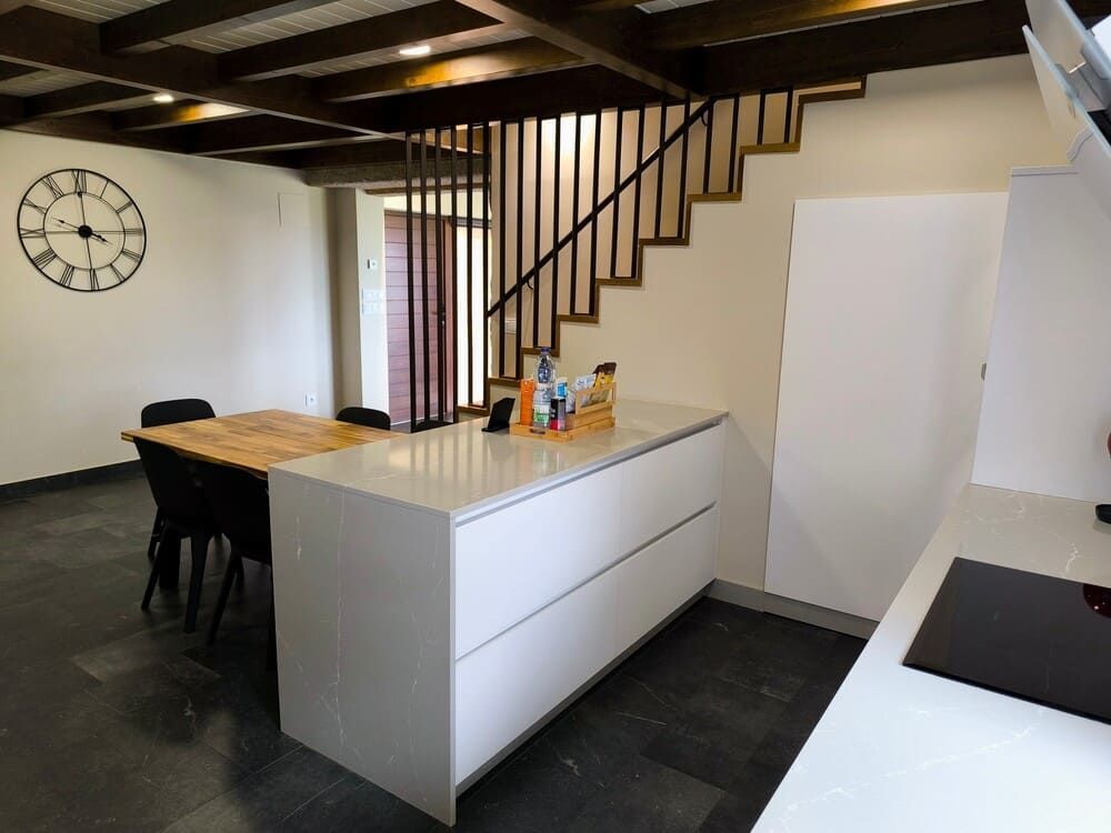 Una cocina con una mesa y sillas y un reloj en la pared.