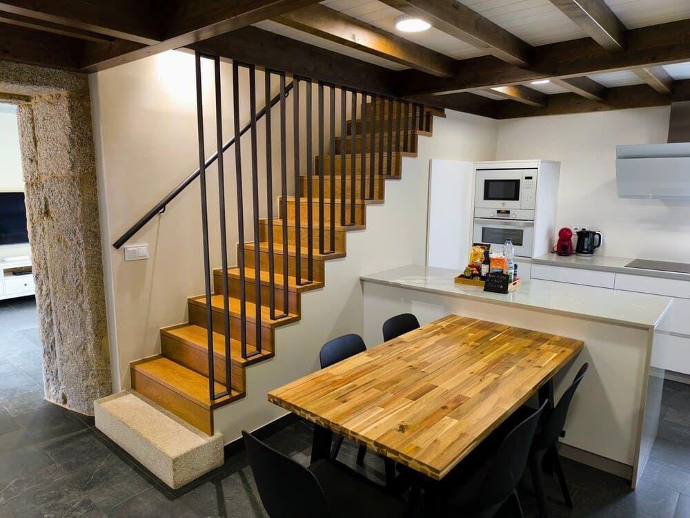 Una cocina con escaleras de madera y una mesa y sillas de madera.