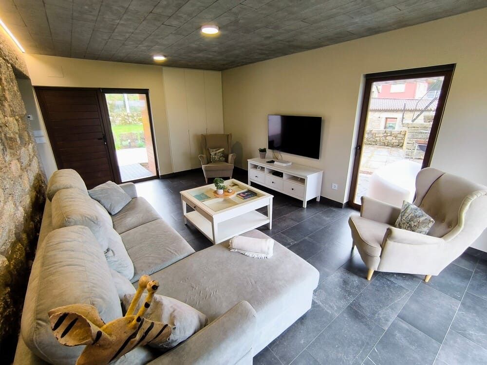 Una sala de estar con sofá, sillas, mesa de café y televisión.