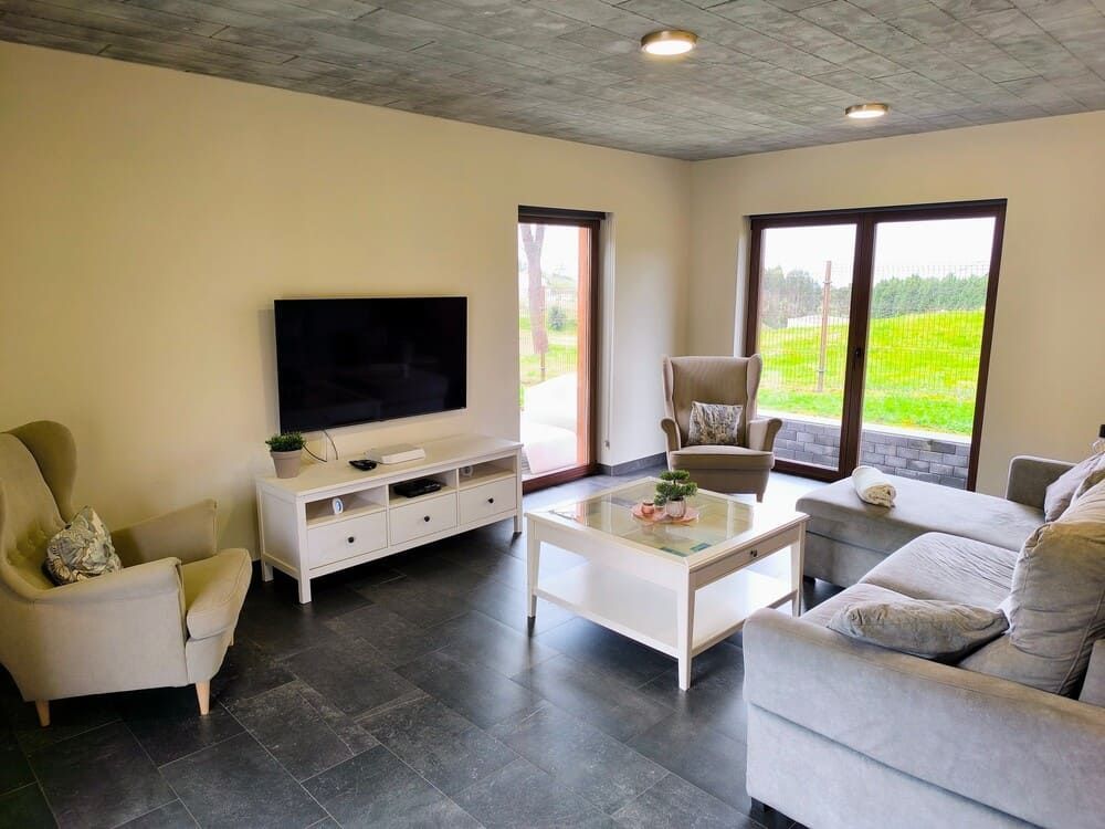 Una sala de estar con sofá, sillas, mesa de café y televisión.