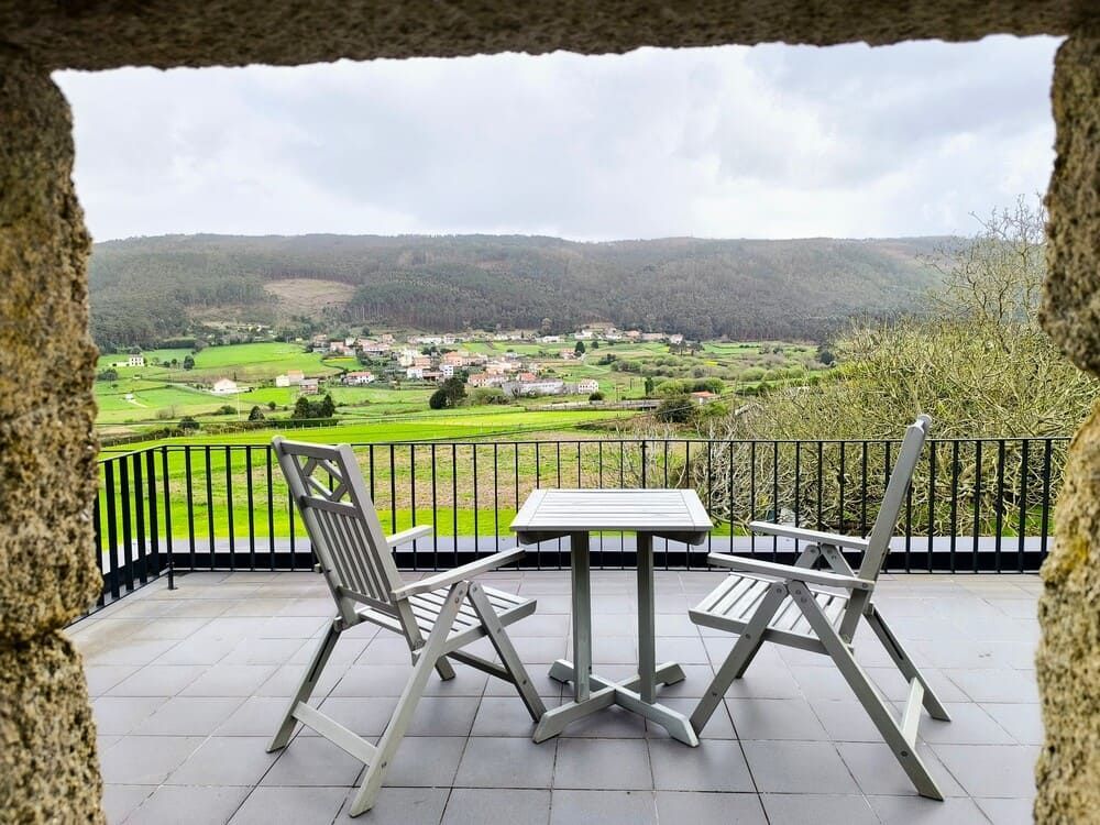 Una mesa y sillas en un balcón con vistas a un valle.