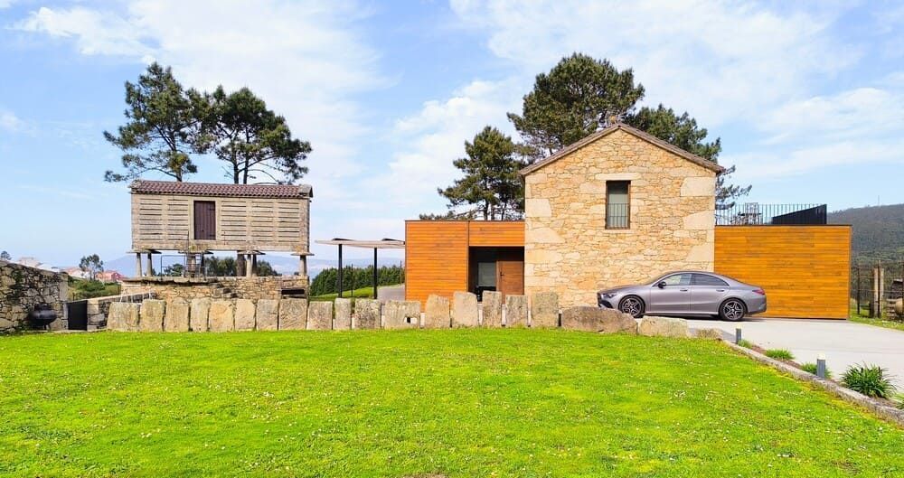 Un coche está aparcado delante de una casa en un campo de hierba.