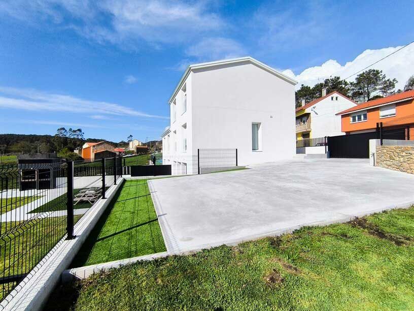 Una casa blanca con una entrada y una valla delante de ella.