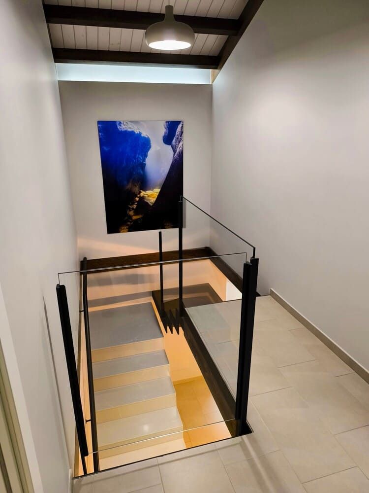 Una escalera con barandilla de cristal y un cuadro en la pared.