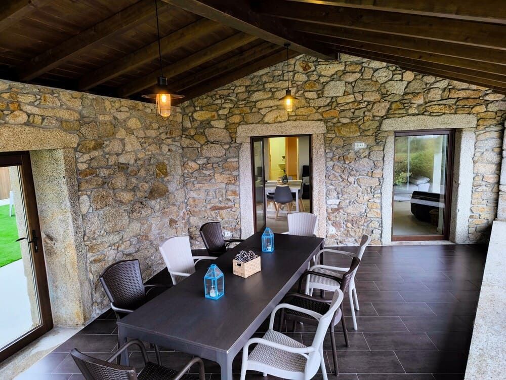 Un patio con una mesa y sillas frente a un muro de piedra.