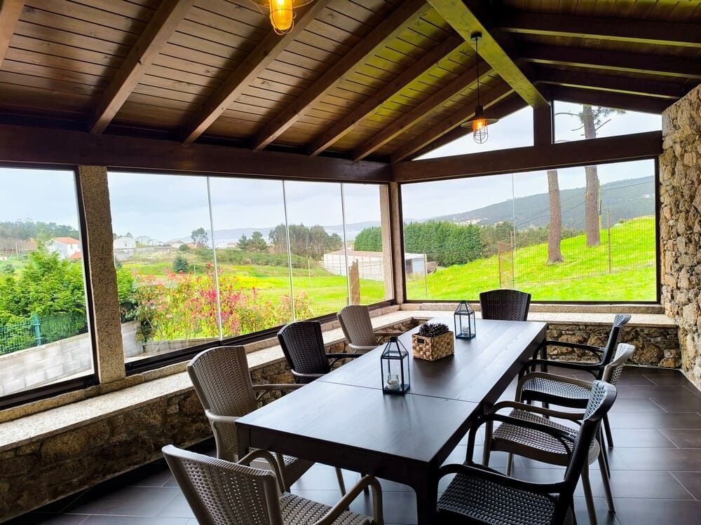 Un comedor con mesa y sillas y vista a un campo.