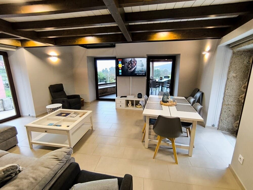 Una sala de estar con un sofá, una mesa, sillas y un televisor.