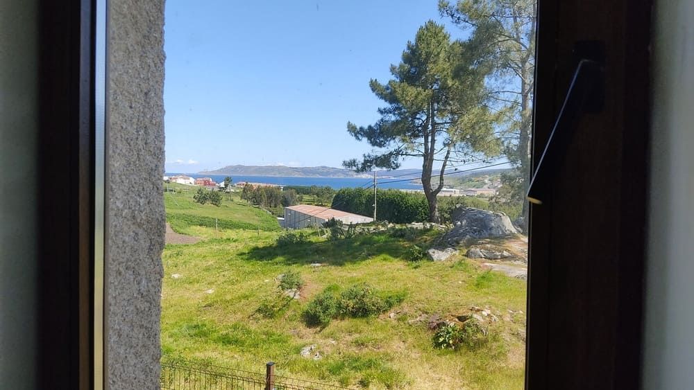 Una ventana con vista a un campo y al océano.