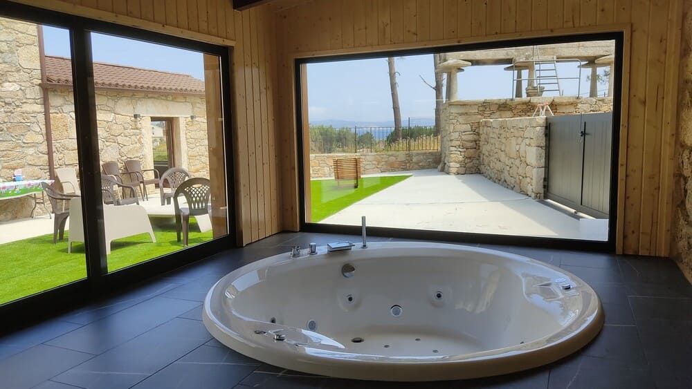 Hay un jacuzzi en el medio de la habitación con una ventana grande.