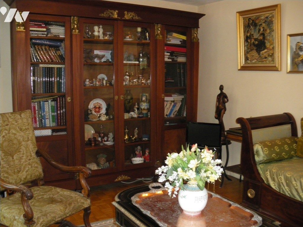 Vitrine en bois sombre remplie de livres et d'objets de collection dans un salon ; meuble ancien.