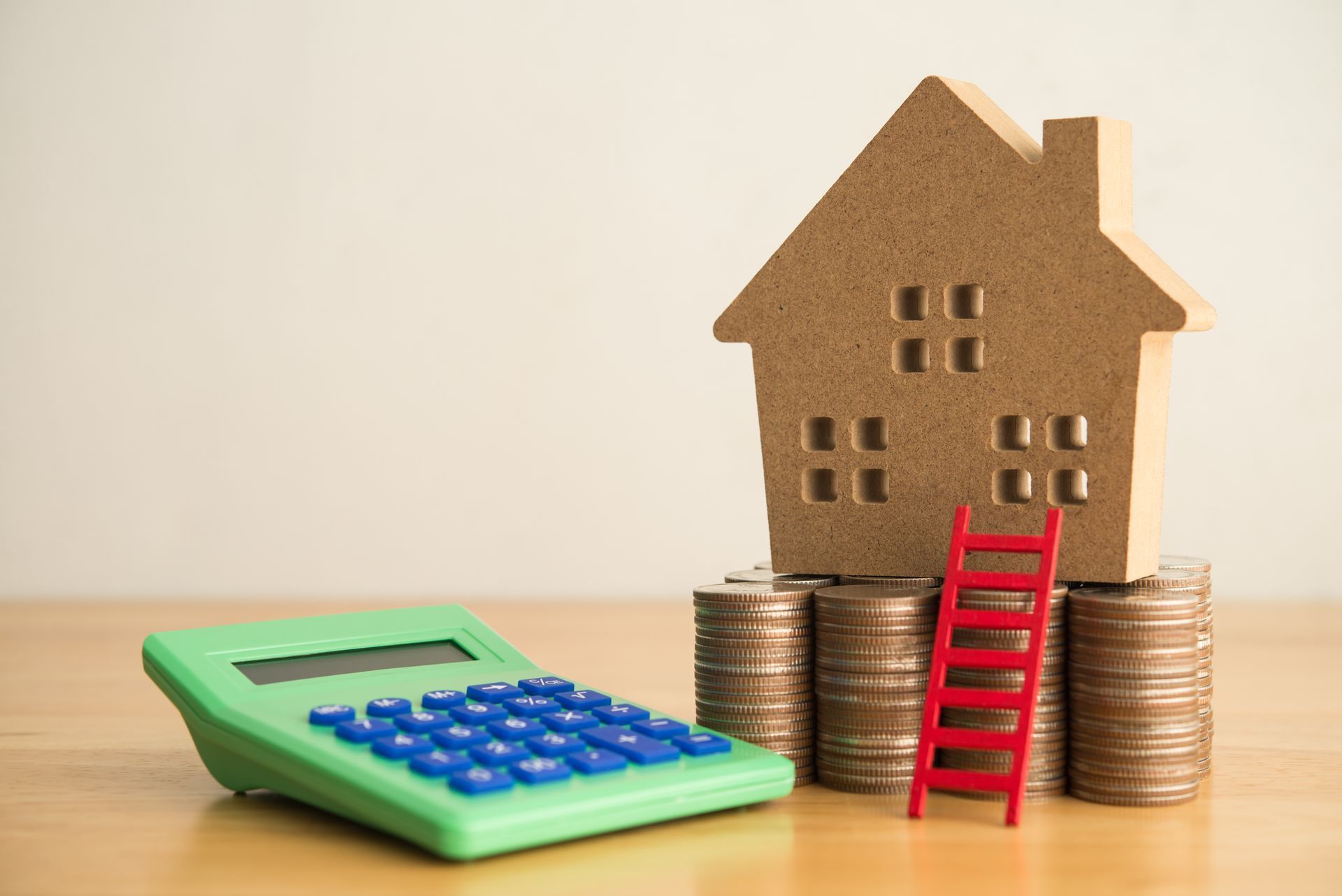 Une petite maison en bois, des pièces de monnaie et une calculatrice