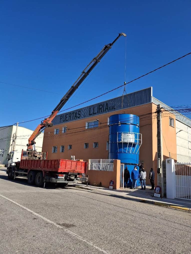 Un camión con una grúa acoplada está estacionado delante de un edificio.