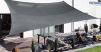 Una gran sombrilla gris está colocada encima de un patio al lado de una casa.