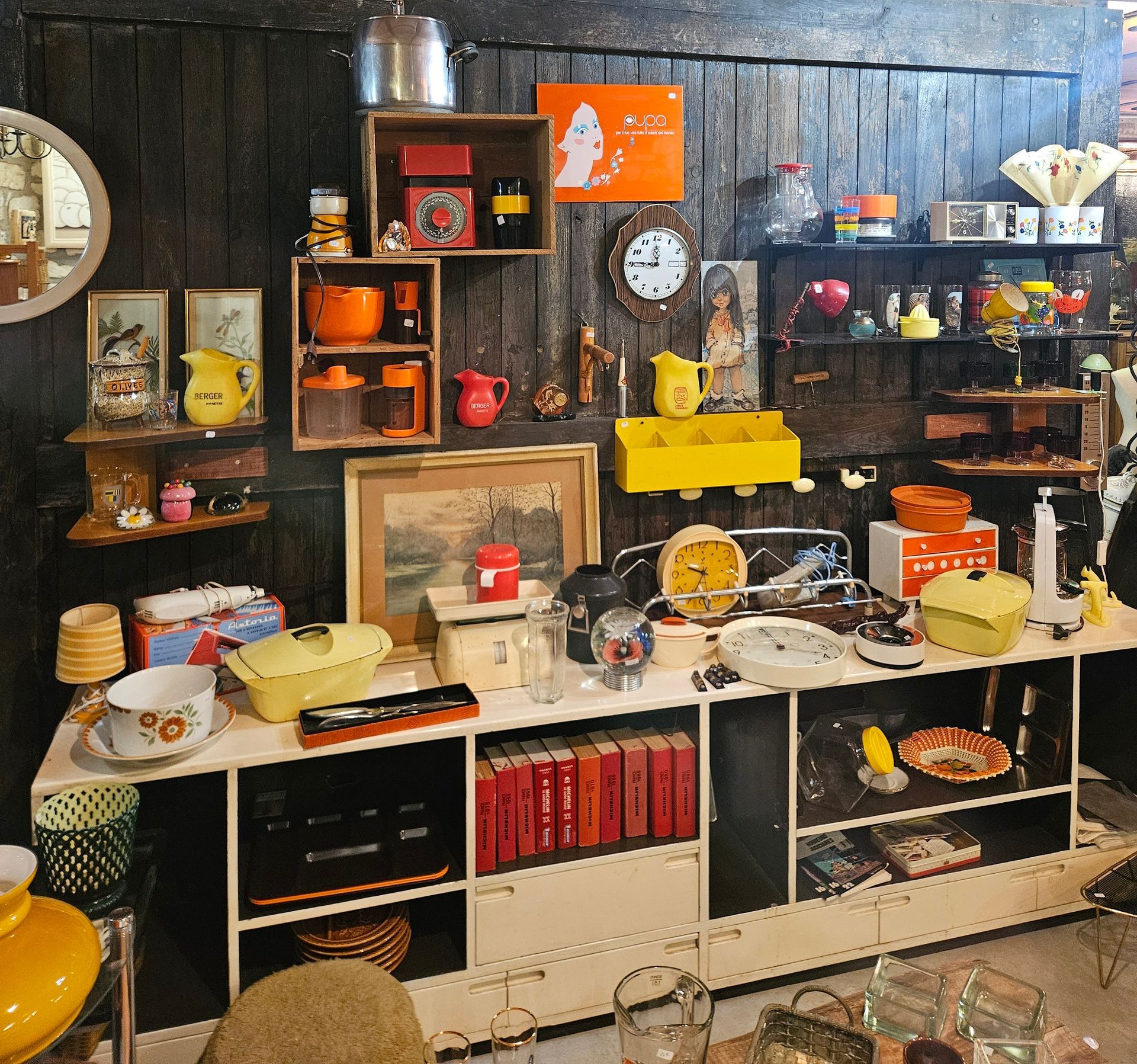 Objets anciens disposés sur une table : vases, statues, bougies et assiettes décoratives.