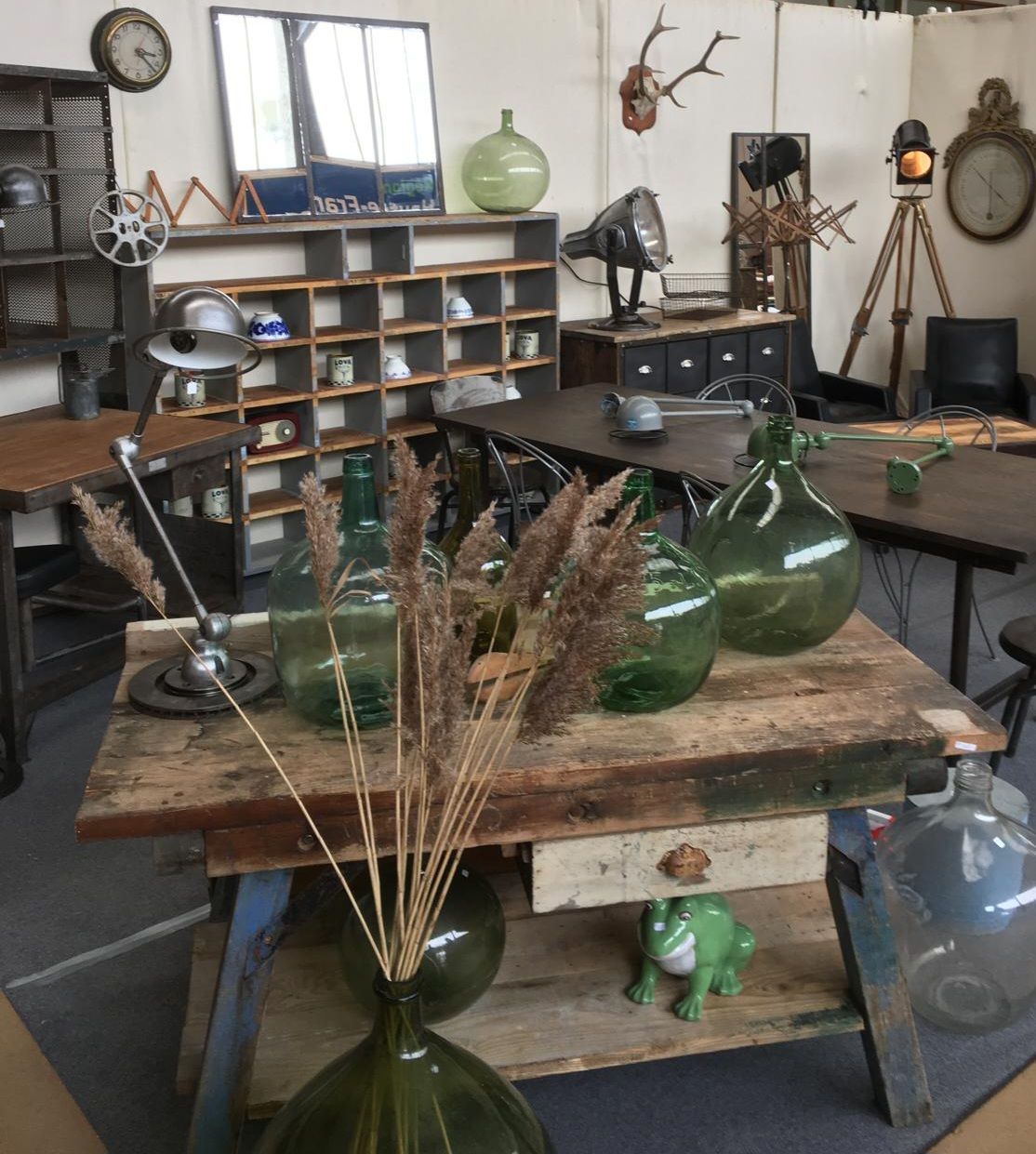 Intérieur d'une boutique vintage : tables en bois, étagères, bouteilles en verre, éléments métalliques, esthétiques rustiques.