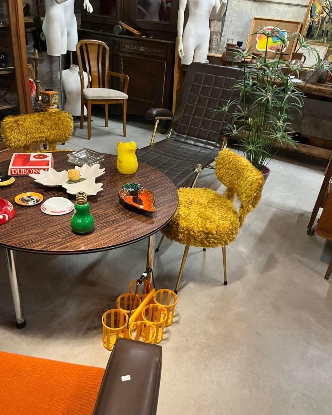 L'intérieur d'un magasin de meubles rétro avec des chaises, des tables et des objets décoratifs de styles variés.