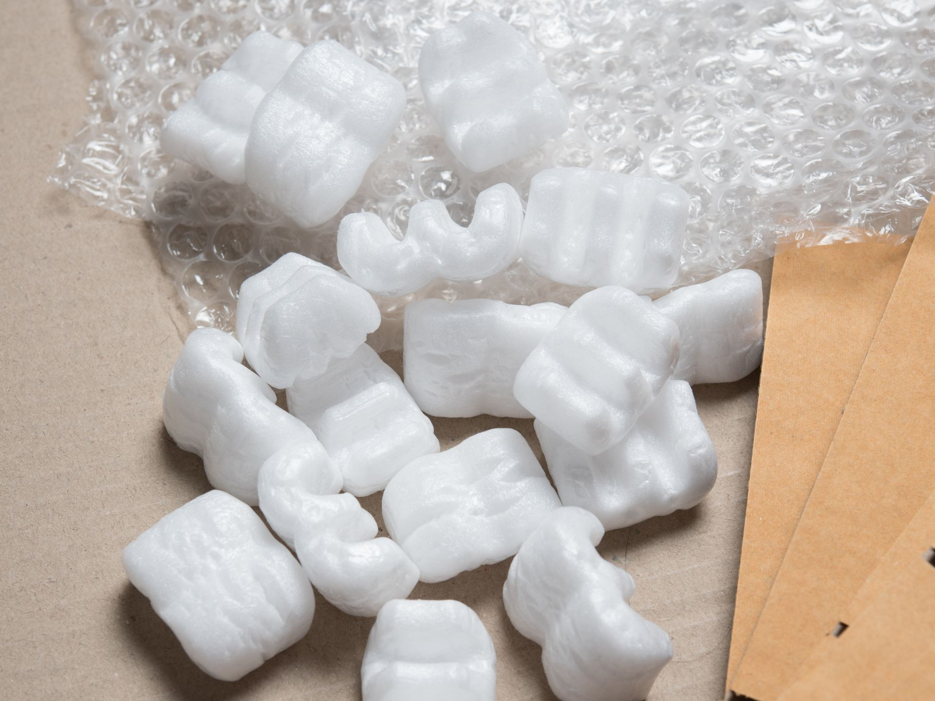 Deux déménageurs en uniforme transportent un canapé gris à travers une pièce lumineuse où des cartons empilés sont visibles en arrière-plan.